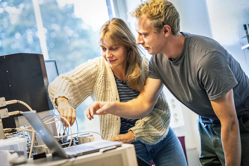Two researchers working with electronic lab equipment. Photo.