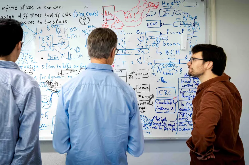 Lärare och två studenter vid en whiteboardtavla